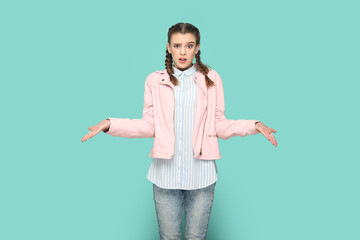 Portrait of confused angry teenager girl with braids wearing pink jacket standing with spread...