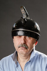 An eccentric man with a teapot on his head narrows his eye mysteriously. - 688153242