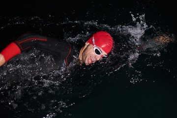 A determined professional triathlete undergoes rigorous night time training in cold waters,...