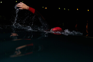 A determined professional triathlete undergoes rigorous night time training in cold waters,...