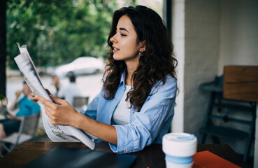 Focused woman reading newspaper in cafe