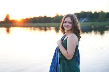 Portrait of young charming teenager girl with a shiny hair stands the bridge at lake enjoying serene quiet peaceful atmosphere in nature.