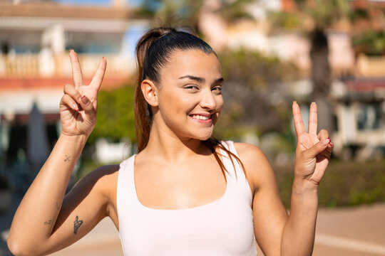Young pretty brunette woman showing victory sign with both hands