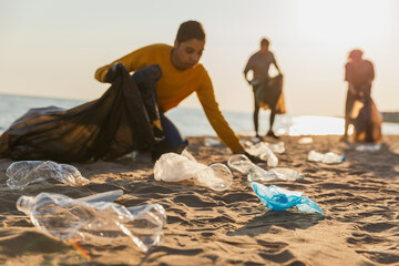 Earth day. Volunteers activists collects garbage cleaning of beach coastal zone. Woman mans with...