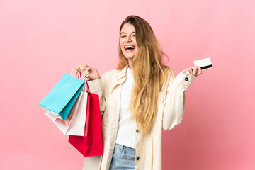 Young woman with shopping bag isolated on pink background holding shopping bags and a credit card - obrazy, fototapety, plakaty