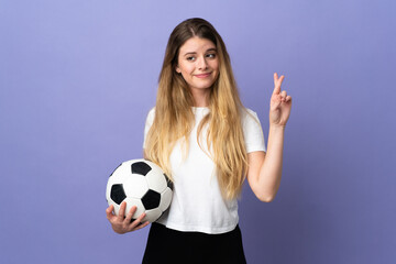 Young blonde football player woman isolated on purple background with fingers crossing and wishing the best