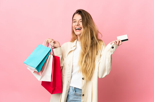 Young woman with shopping bag isolated on pink background holding shopping bags and a credit card