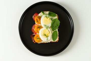 Diet sandwich with vegetables and seasoning on a black plate.