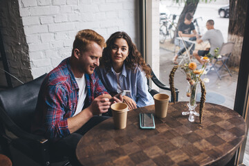 Young modern couple sitting at table in cafe