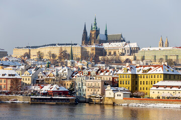 Snowy Prague Lesser Town with gothic Castle above River Vltava, Czech republic