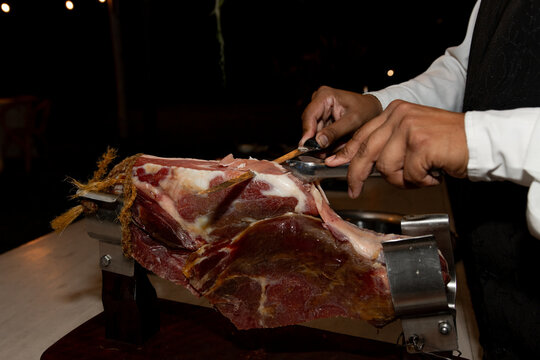 Manos cortando jam&oacute;n crudo con cuchilla