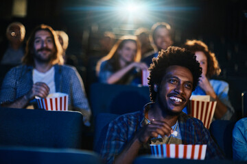 Smiling young man watching movie at the cinema