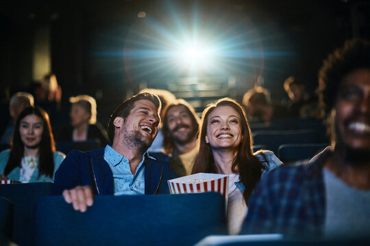 Smiling young couple watching a film in movie theater