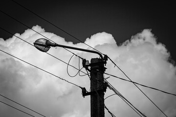 A street light pole against a background of blue sky and white clouds