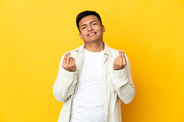 Young Ecuadorian man isolated on yellow background making money gesture