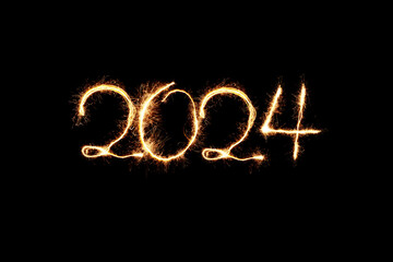 Obraz na płótnie Canvas New Year 2024 sparkler golden light. Sparklers draw figures 2024. Bengal lights and letter. Holidays 2024 card.