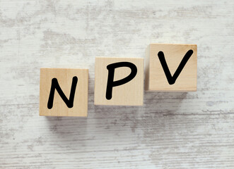 wooden blocks on a gray background. text NPV , Net Present Value concept.