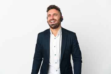 Telemarketer man working with a headset isolated on white background laughing