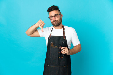 Barber man in an apron showing thumb down with negative expression