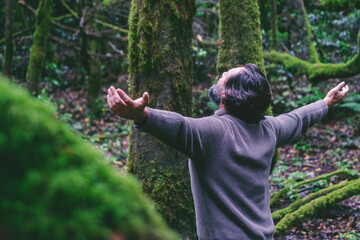Carefree man with outstretched arms standing in the woods.Relaxed and meditating. Happiness and...
