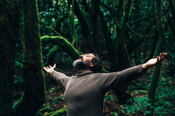 Portrait of overjoyed man outstretching arms in outdoors leisure activity with dark beautiful green...