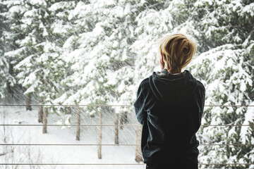 Ein Junge steht am Fenster und beobachtet den Schneefall