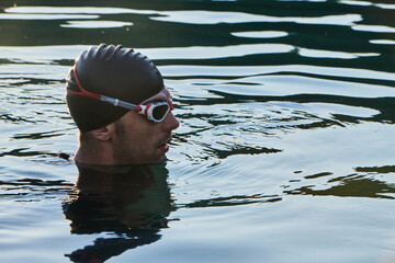 A triathlete finds serene rejuvenation in a lake, basking in the tranquility of the water after an...