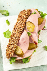 Healthy rye bun sandwiches with ham and pickled cucumbers on a light background top view. copy space