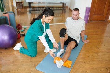 Nurse explaining patient how to do myofascial release with foam roller