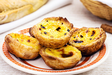 Traditional Portuguese dessert of pastel de nata, and bree de lis and bread in the background,...