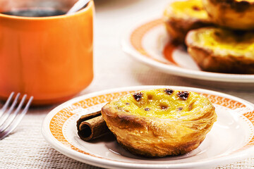 Traditional Portuguese dessert of pastel de nata, and bree de lis and bread in the background,...