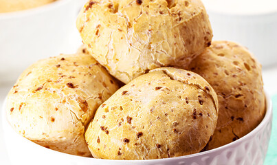 bowl full of traditional brazilian cheese bread or cheese biscuit, served crispy and hot, with coffee