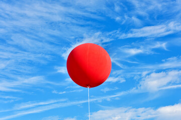 Red balloon. A giant inflatable red advertising balloon floats in the sunny blue sky.
