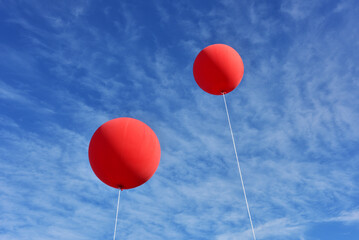 Red balloons. A giant inflatable red advertising balloon floats in the sunny blue sky..