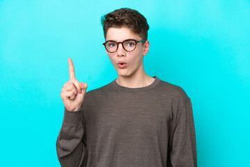 Teenager Russian man isolated on blue background intending to realizes the solution while lifting a finger up - obrazy, fototapety, plakaty