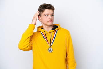 Teenager Russian man with medals isolated on white background having doubts and with confuse face expression