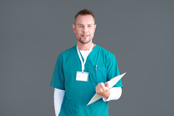 Portrait of male medical nurse in green scrubs holding clipboard