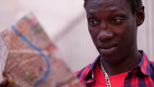 portrait of young migrant trying to orient himself by consulting the map of the city