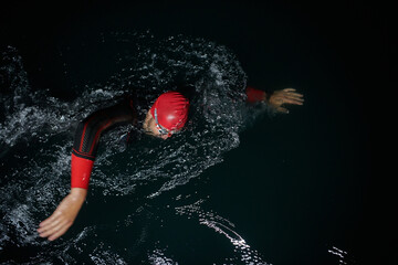 A determined professional triathlete undergoes rigorous night time training in cold waters,...