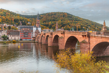 Obraz premium View on the Karl Theodor Bridge (German: Karl-Theodor-Brücke) and the old gate in the german city Heidelberg during early morning on a cloudy day. Heidelberg on Neckar river.