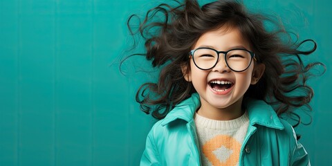 chłopczyk śmiejący się w okularach na niebieskim tłe w czarnych długich włosach - obrazy, fototapety, plakaty