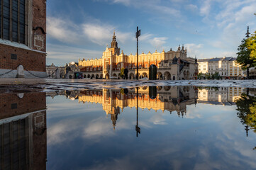 Renaissance Cloth Hall on Krakow Main Square reflecting in the water puddle, sunny morning, Cracow, Poland