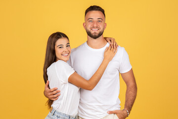 Happy young european couple in white t-shirts, enjoy romantic date together, hugs