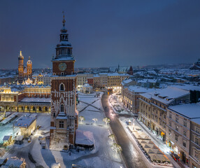 Night view of snow covered Main Square with Town Hall tower and Christmas Fairs in Krakow, Poland