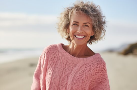 Portrait Of A Very Healthy Mature Woman With Curly White Hair And A Pink Sweater At The Beach