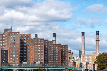 Fototapeta na wymiar Identical brick apartment blocks in the East Village, New York City, NY, USA along the East river with in the background the smokestacks of the energy plant for the city