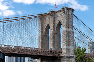 Fototapeta premium Low angle view of one of the towers of the Brooklyn Bridge with Lower Manhattan, New York City in background 