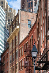 Fototapeta na wymiar New York City, NY, USA-October 15, 2023; Low angle view of some of the historic buildings on Stone Street of former New Amsterdam in Manhattan with modern high rise in the background