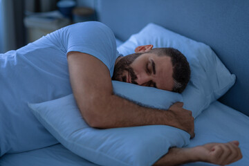 Peaceful Guy Sleeping Embracing Pillow Lying In Bed At Home