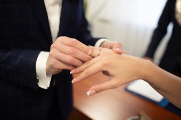 Pan Młody zakłada obrączkę na palec. The groom puts the ring on his finger.	 - obrazy, fototapety, plakaty